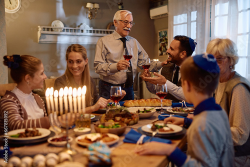 Happy Jewish father and son toasting during Hanukkah family celebration in dining room.