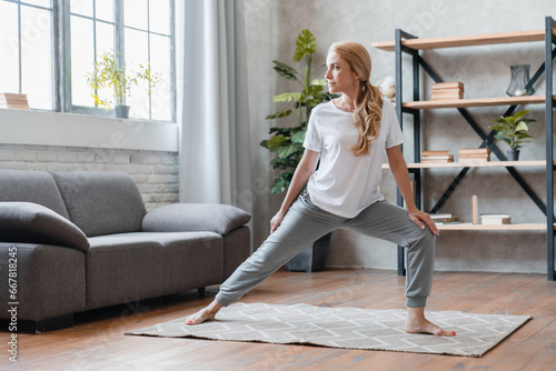 Home stretching, yoga exercises. Mature Caucasian woman in sporty clothes working out, doing physical training at home, losing weight, burning calories