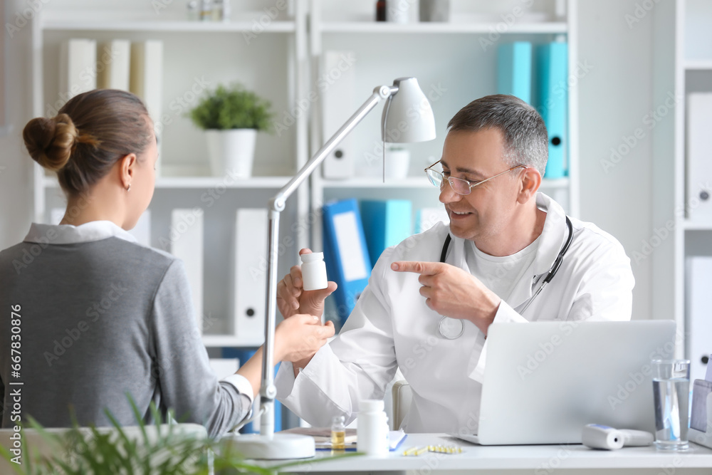 Mature male doctor giving pill bottle to patient in clinic Mature male doctor giving pill bottle to patient in clinic
