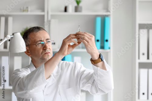 Mature male doctor with syr...