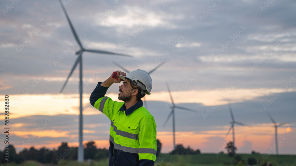Obraz premium Service engineers checking system of windmill with tablet. Wind turbines generate electricity. Clean and Renewable energy concept.