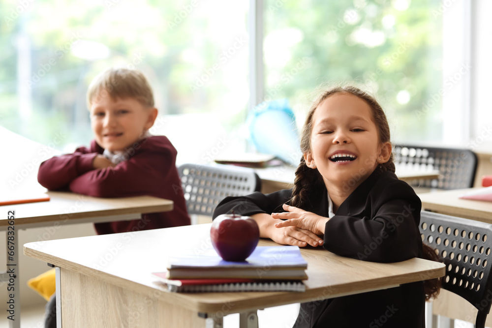 Happy classmates sitting at desks in classroom Happy classmates sitting at desks in classroom