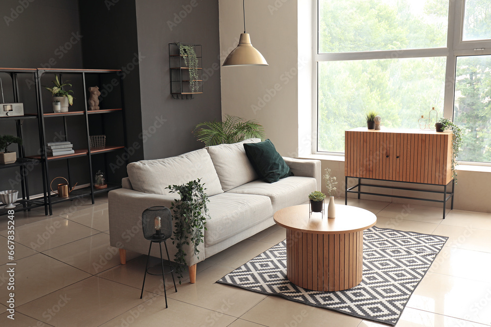 Obraz premium Interior of modern living room with comfortable grey sofa and wooden coffee table