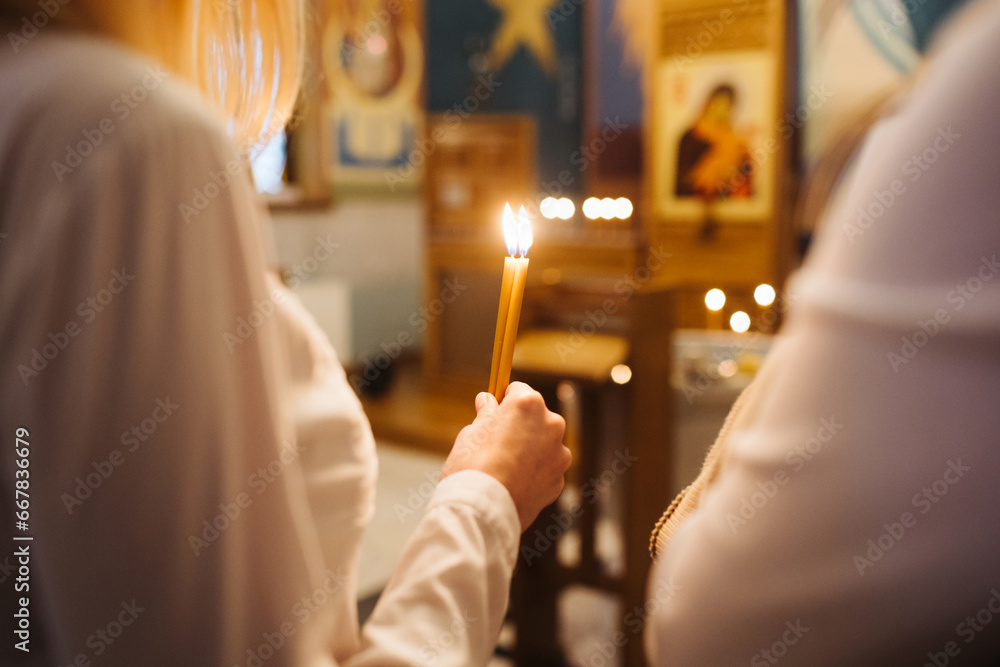 Orthodox church candle background. Hand holding candle during ceremony. Baptism ceremony in East of Europe. - obrazy, fototapety, plakaty 