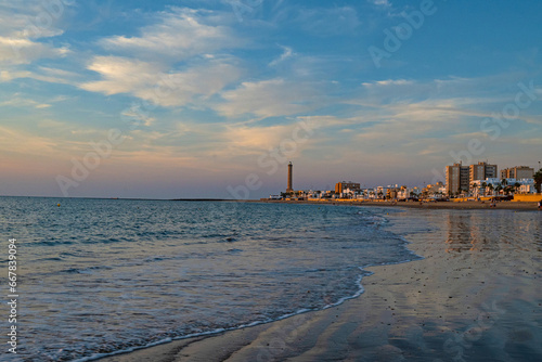 Regla beach with church and lighthouse in Chipiona in warm evening light photo