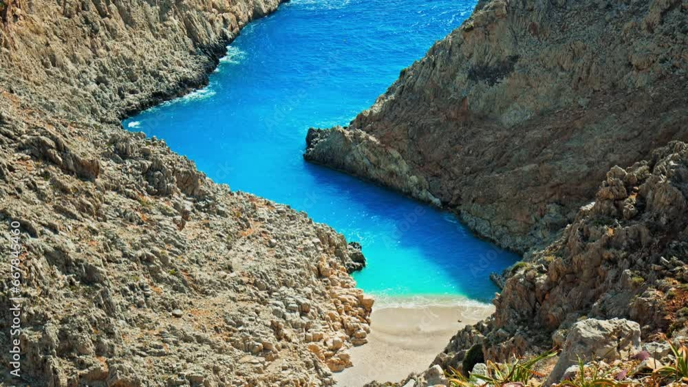 View of the sandy beach in a cove surrounded by rock formations at Seitan Limania, Crete. Stunning crystal blue beach, picturesque panoramic view from the cliffs in Crete, Greece. View of the sandy beach in a cove surrounded by rock formations at Seitan Limania, Crete. Stunning crystal blue beach, picturesque panoramic view from the cliffs in Crete, Greece.