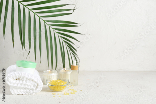Composition with spa accessories, cosmetics and palm leaf on light table