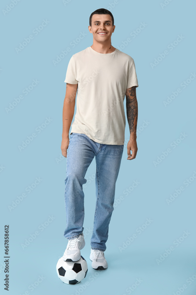 Handsome young man with soccer ball on blue background Handsome young man with soccer ball on blue background