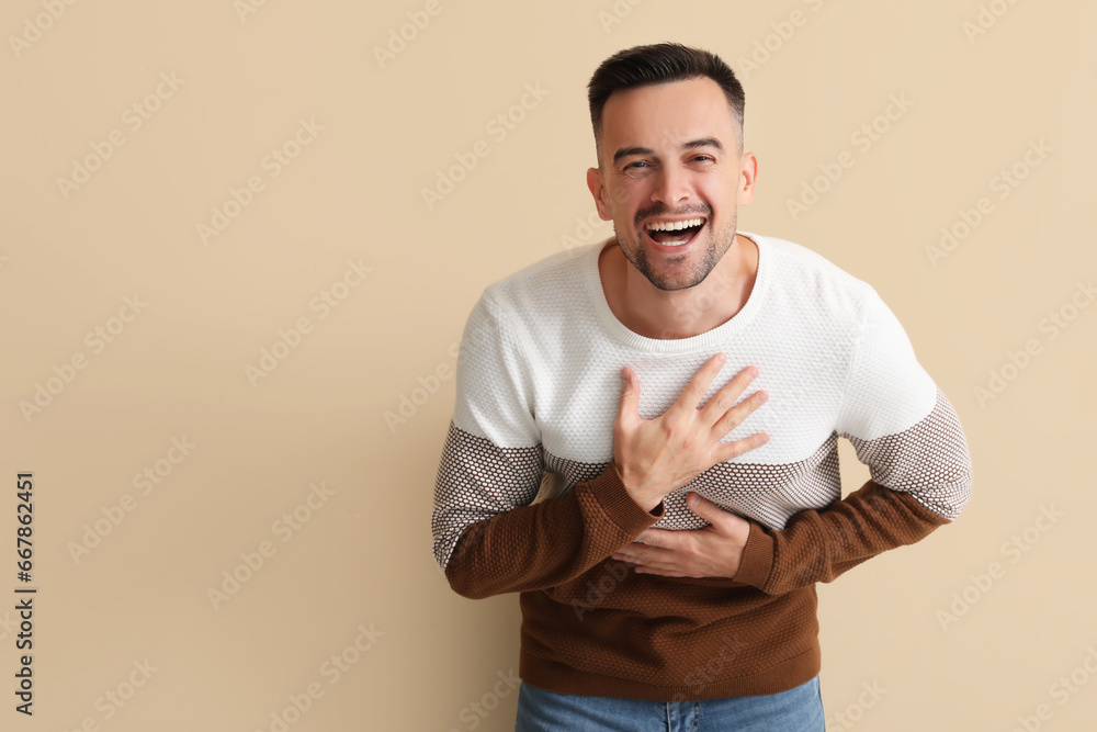Happy young man laughing on beige background Happy young man laughing on beige background