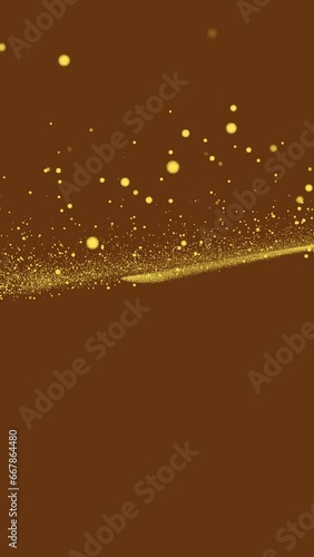 Gold tiny dots glitter on brown background that fly up from the middle of the frame. Vertical abstract stars backdrop party or Christmas holidays and New Year concept with copy space.
