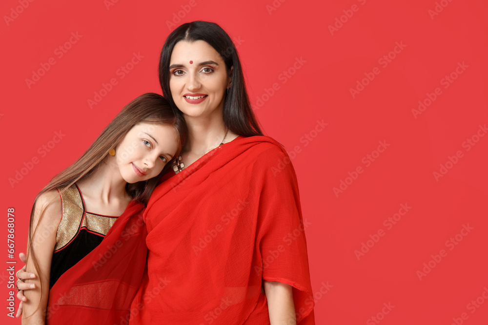 Beautiful mother with her daughter in sari on red background. Divaly celebration Beautiful mother with her daughter in sari on red background. Divaly celebration