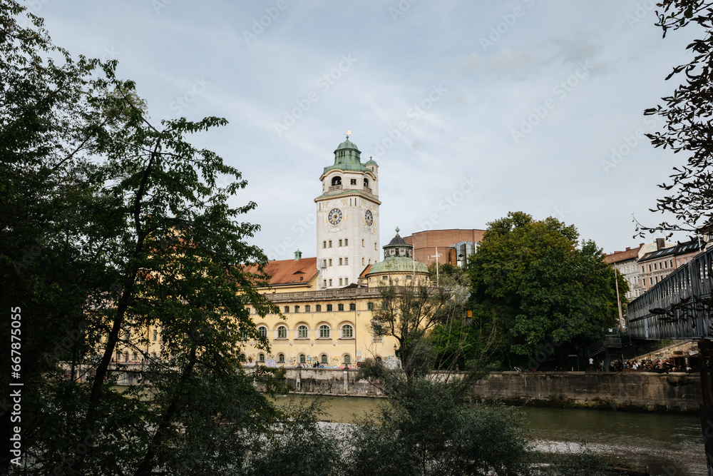 Tower of the Müller’sches Volksbad public pool in Munich Germany, Isar river and trees, cloudy day