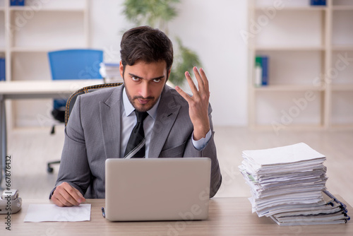 Young male employee and too much work in the office