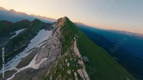 Aerial view mountain ridge with gazex industrial tube rock natural texture snow at sunset. FPV sport drone amazing shot picturesque cliff alpine valley sunrise landscape ski resort cable car pillar