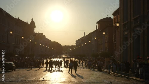 Silhouette group of tourists queuing to enter Vatican to visit cathedral of St. Peter's on Via della Conciliazione street (Road of the Conciliation) in evening during sunset. Shooting in slow motion. photo