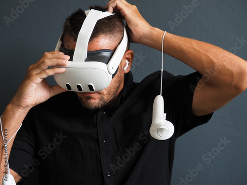 Man puts on mixed virtual reality headset with VR controllers.