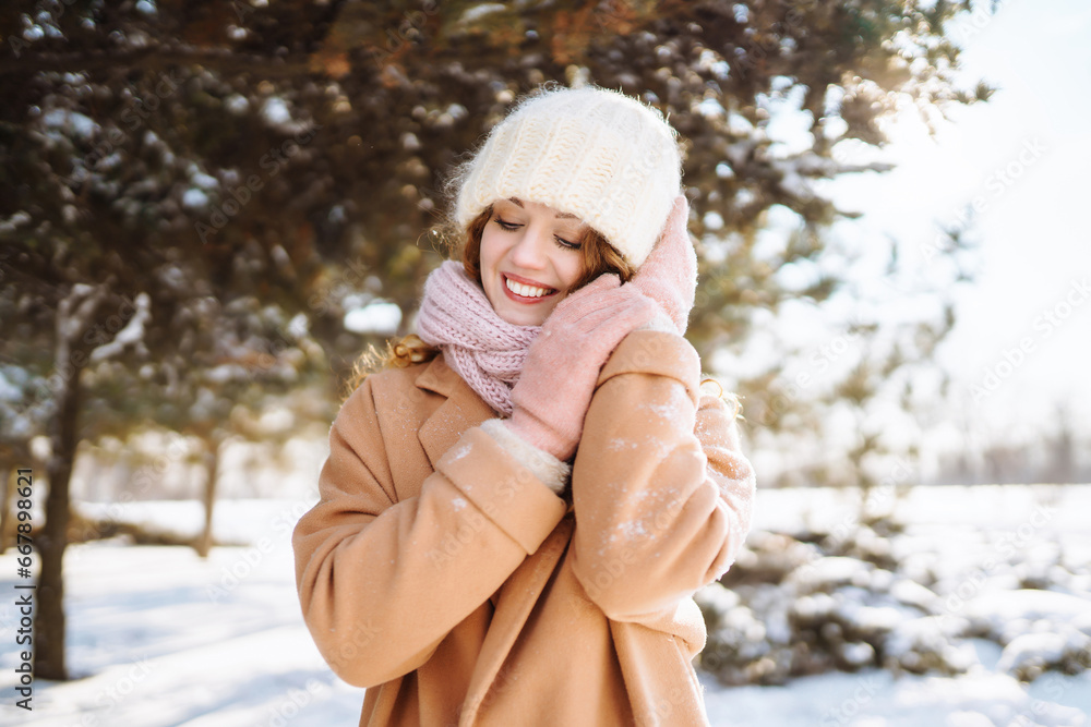 Obraz premium Beautiful portraits of a woman in a winter forest. She enjoys the first snow during the New Year holidays. Walk in winter forest.