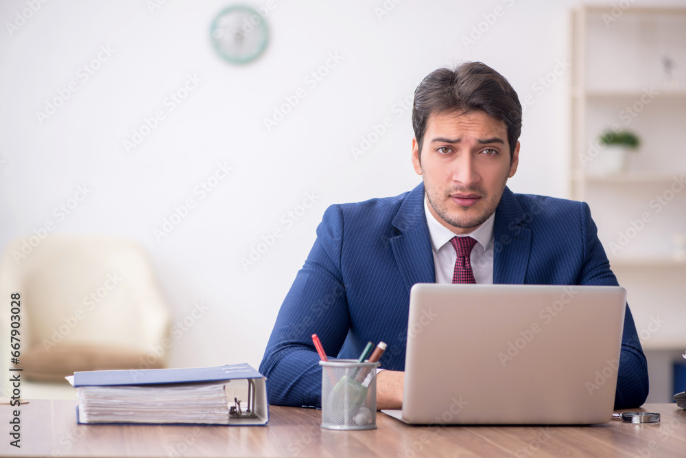 Young male employee unhappy with excessive work in the office Young male employee unhappy with excessive work in the office