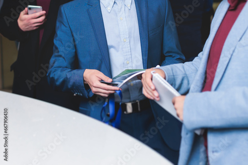 Process of checking in on a conference congress forum event, registration desk table, visitors and attendees receiving a name badge and entrance wristband bracelet and register electronic ticket