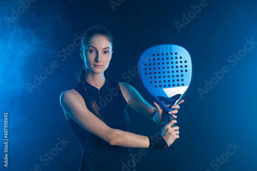 Padel tennis player with racket on tournament. Girl athlete with paddle racket on court with neon colors. Sport concept. Download a high quality photo for design of a sports app or tour events. photo
