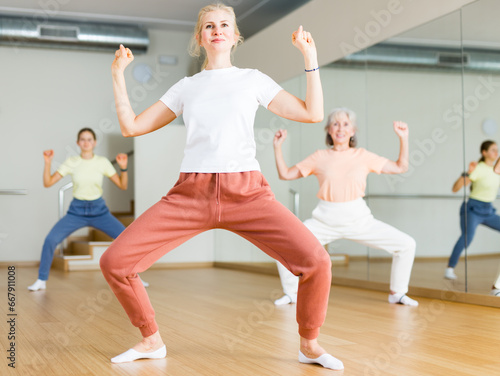 Woman doing squats on group fitness training in studio.
