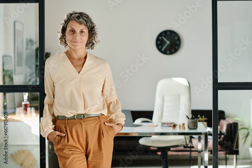 Foto Smiling mature female chief executive officer in beige blouse and brown pants st