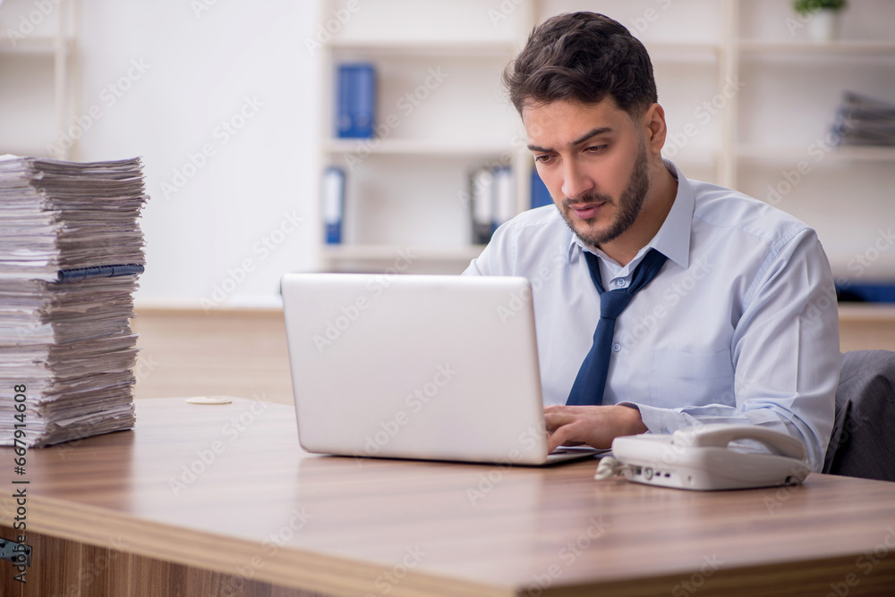 Young male employee and too much work in the office Young male employee and too much work in the office