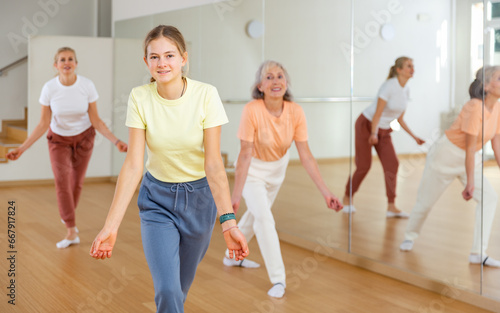 Young positive teenager girl dancing during group class in dance center