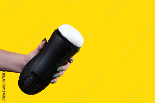 Sex toys for men. An artificial vagina for masturbation in the hands of a girl on a yellow background. Male massager. Sex shop Adult store photo