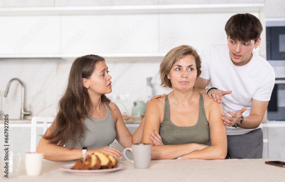 Adult children calm their mother after a domestic quarrel