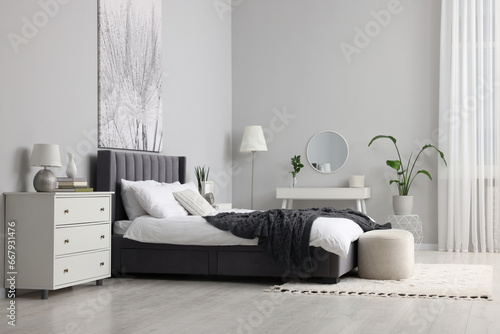 Stylish bedroom interior with large comfortable bed and dressing table