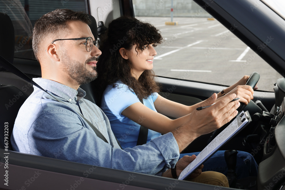 Driving school. Happy student passing driving test with examiner in car at parking lot Driving school. Happy student passing driving test with examiner in car at parking lot