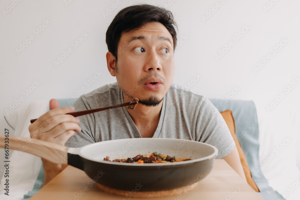 Happy funny face of asian man eating homemade food in the pan with chopsticks. Happy funny face of asian man eating homemade food in the pan with chopsticks.
