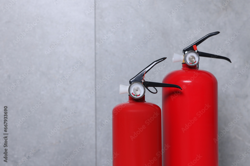 Obraz premium Fire extinguishers near grey wall, space for text