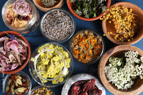 Many different herbs in bowls on blue wooden table, flat lay