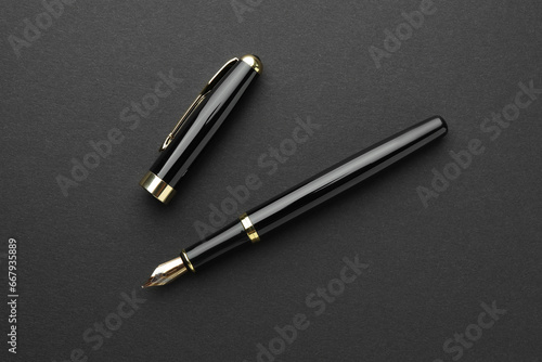 Stylish fountain pen with cap on black background, flat lay