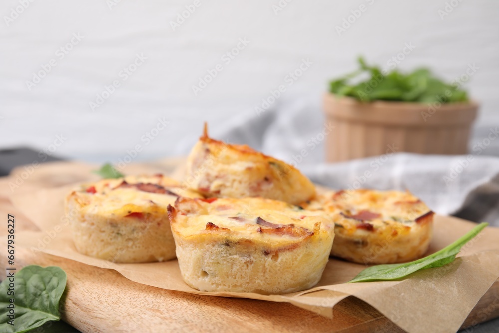 Delicious egg muffins with cheese and bacon on wooden board, closeup. Space for text