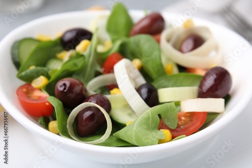 Bowl of tasty salad with leek and olives on table, closeup