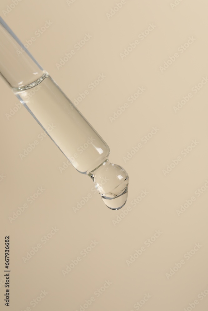 Dripping cosmetic serum from pipette on beige background Dripping cosmetic serum from pipette on beige background