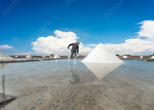 A salt field worker harvesting salt in ancient Tainan county in Taiwan that shows the local culture, livelihood and real life,