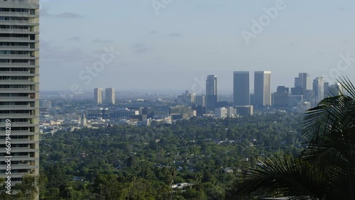 Aerial Panning Shot Of Modern Buildings And Green Trees In City Against Sky - West Hollywood, California photo