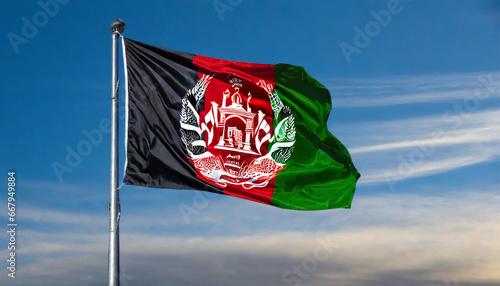 Close up view of an Afghanistan flag waving on a flagpole, with blue sky background and copy space