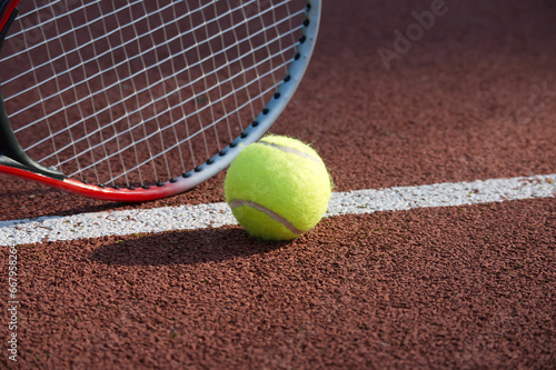 Yellow tennis ball and racquet on hard court surface © NetPix
