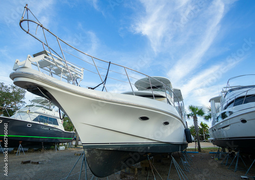 A leisure yacht sits in dry storage on stilts in a boatyard for repair