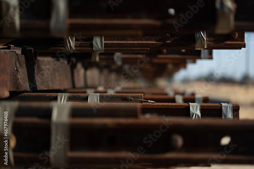 Closeup of a neat stack of materials for laying train tracks: railway sleepers (railroad ties) and steel rails are tidily arranged.