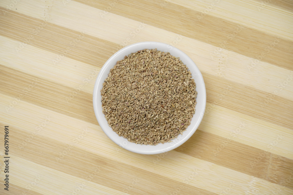 Top view of carom seeds in bowl on wooden background Top view of carom seeds in bowl on wooden background