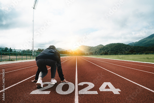 Happy New Year 2024 symbolizes the start of the new year. Woman preparing to run on the athletics track is engraved with the year 2024. start challenge goal of planning health and business to success