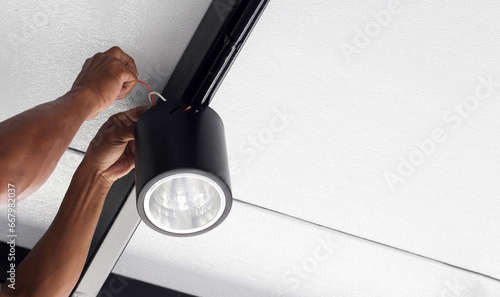 Hands of an electrician installing a light on the ceiling.