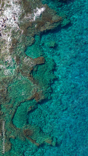 A top down aerial photo of the blue waters of Hawaii and coral reefs off of the Big Island. With beautiful blue colors and texture of land