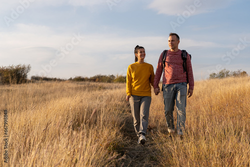 Young couple hiking through autumn fields and hills during warm day. Weekend  leisure  sport